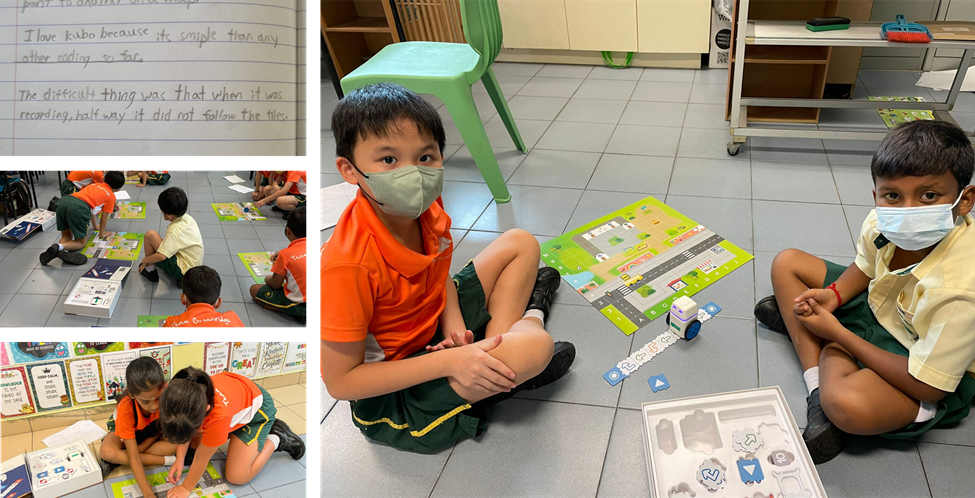Two masked students sit on a classroom floor with a KUBO coding robot and colorful activity mat.